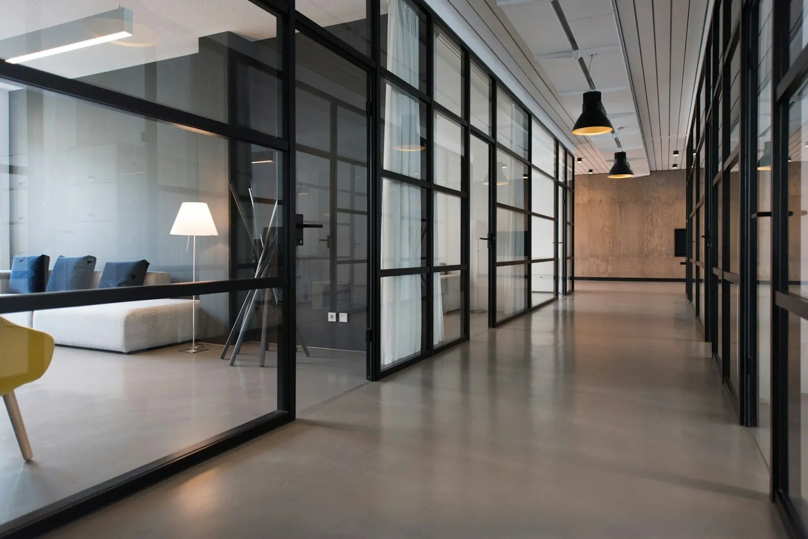 A quiet modern office: glass partitions, a lamp, and a seating corner.